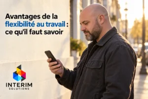 Homme debout dehors consulte son smartphone.